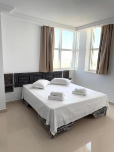 a white bedroom with a bed with two towels on it at Le charbon élégant in Bin Rhilouf