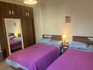a bedroom with two beds with purple covers at Cozy appartment in hrajel in Dir‘alī