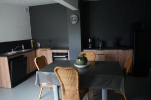 a kitchen with a table with chairs and a kitchen with black walls at Chez Rachel in Mérélessart