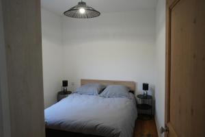 a bedroom with a bed with white sheets and a light at Chez Rachel in Mérélessart
