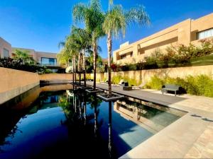 a pool of water with palm trees and a building at Cozy appartement Marrakech in Marrakesh
