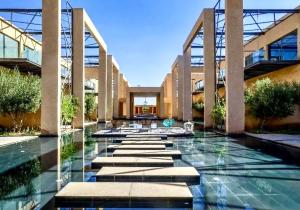a swimming pool in a building with a fountain at Cozy appartement Marrakech in Marrakesh