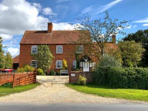 an old red brick house with a fence at Manor Farm in Poundon