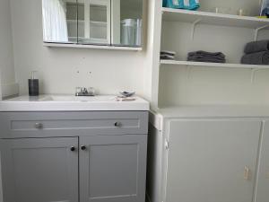 a white bathroom with a sink and a mirror at Texada Hunter Hiker friendly suite in Vananda +4 photos