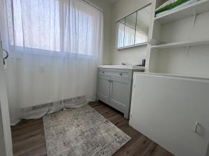 a white kitchen with a sink and a window at Texada Hunter Hiker friendly suite in Vananda