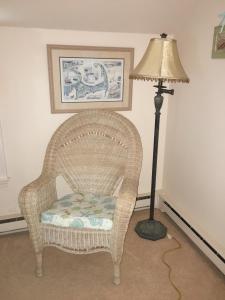 a lamp sitting next to a wicker chair next to a floor lamp at Bayside Bliss in Dennis +19 photos