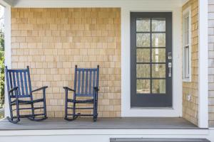 two blue chairs sitting on the porch of a house at Sea Winds in Brewster