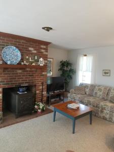 ein Wohnzimmer mit Sofa und gemauertem Kamin in der Unterkunft Summer Sand in Dennis