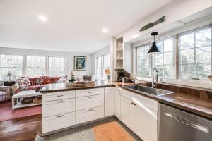 a kitchen with white cabinets and a living room at Sunny Days in Brewster +15 photos