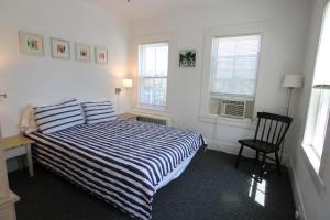 a bedroom with a bed and a chair and windows at High Tide Lower Level in Provincetown