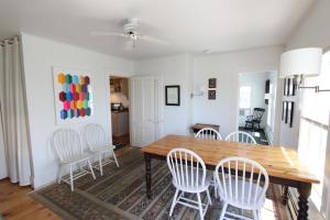 a dining room with a wooden table and white chairs at High Tide Upper Level in Provincetown