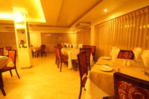 a dining room with tables and chairs with white tablecloths at Hotel Ornate in Dhaka