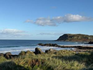 a beach with rocks and the ocean with a mountain at Shanawee in Gleneely +11 photos