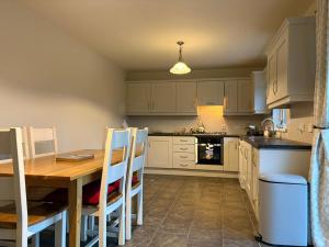 a kitchen with a wooden table and white cabinets at Shanawee in Gleneely