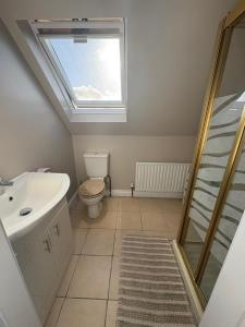 a bathroom with a toilet and a sink and a window at Shanawee in Gleneely