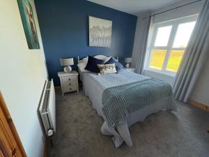 a blue bedroom with a bed and a window at Shanawee in Gleneely