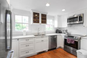 a kitchen with white cabinets and stainless steel appliances at Harbor Breeze Townhouse in Provincetown