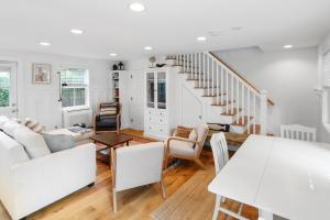 a living room with white furniture and a staircase at Harbor Breeze Townhouse in Provincetown