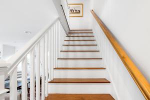 a white staircase with wood treads and white walls at Harbor Breeze Townhouse in Provincetown