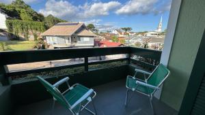 two chairs on a balcony with a view of a church at Apto 2D ensolarado, sacada e garagem, centro in Nova Petrópolis