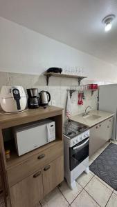 a small kitchen with a stove and a microwave at Apto 2D ensolarado, sacada e garagem, centro in Nova Petrópolis