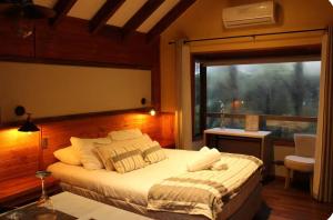 a bedroom with a large bed and a window at Estero El Claro Hotel y Cabañas in Pucón