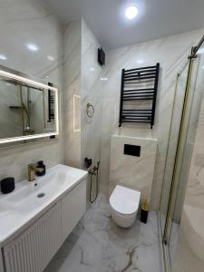 a white bathroom with a toilet and a sink at next apartment lux in Batumi +5 photos