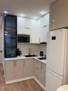 a kitchen with white cabinets and a white refrigerator at next apartment lux in Batumi