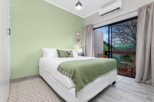 a bedroom with a bed and a large window at Honeysuckle in Tzaneen +11 photos