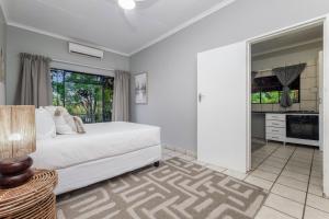 a white bedroom with a bed and a kitchen at Honeysuckle in Tzaneen