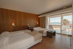 two beds in a hotel room with a view of the ocean at Hotel Arica in Arica +106 photos