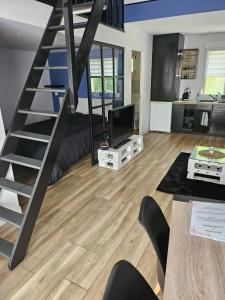 a living room with a staircase and a television at Arboréa, charmant loft in Mirebeau-sur-Bèze