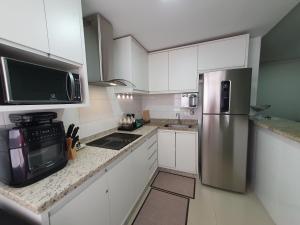 a kitchen with white cabinets and a stainless steel refrigerator at Praia da Graciosa Apartamento 2 quartos in Palmas