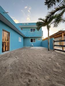 a blue house with a palm tree in front of it at Casa GLEZAR el cuyo in El Cuyo