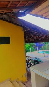 a yellow wall with a picnic table and a tennis court at Serra mineira in Resende