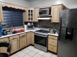 a kitchen with wooden cabinets and a stainless steel refrigerator at Floresta in Manuel F. Martínez