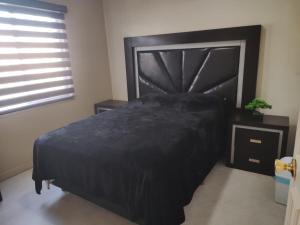 a bedroom with a black bed and a window at Floresta in Manuel F. Martínez