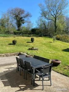 a black table and chairs with a view of a field at Charmant penty pour un séjour calme et reposant in Ergué-Gabéric