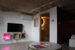a living room with a tv and a table at Le Cocon Troglodyte fraîcheur naturelle in Saint-Étienne-de-Chigny