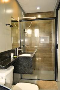 a bathroom with a toilet and a sink and a shower at Real Grandeza - Studios modernos in Aparecida de Goiânia +61 photos