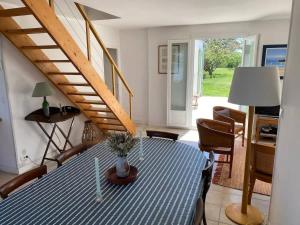 a dining room with a blue table and a staircase at La Villa de la Digue in Saint-Clément-des-Baleines