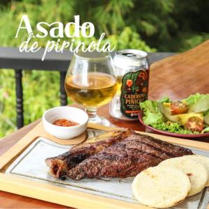 a steak and a glass of beer and a plate of food at MANIPURA in Guaduas