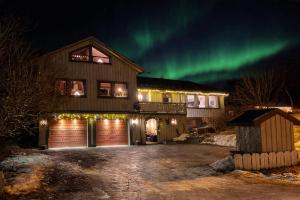 a house with the northern lights in the sky at House under the Aurora Cozy Private Home with Fireplace in Laukvik