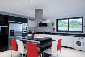 a kitchen with a black counter and red chairs at Villa Vieira Ocean View in Gaula