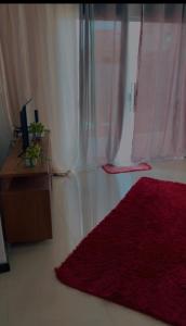 a bedroom with a red rug next to a window at Cada da lanny in Camaçari +9 photos