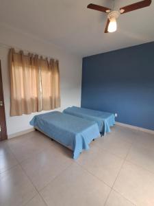 a bedroom with a bed with a blue blanket at Recanto das Violetas in Extrema