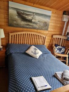 a bedroom with a bed with a blue comforter at Weston's Wood Cabins in Blakeney