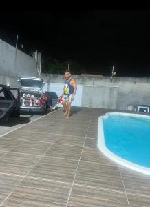 a man is standing next to a swimming pool at Cada da lanny in Camaçari