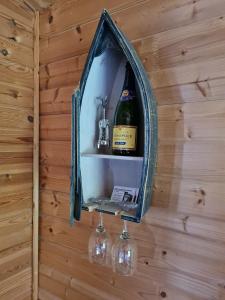 a wall with a mirror with wine bottles and glasses at Weston's Wood Cabins in Blakeney