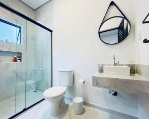 a bathroom with a toilet and a sink and a mirror at Studio 209-AP2 espaço completo ideal para casal in Ubatuba